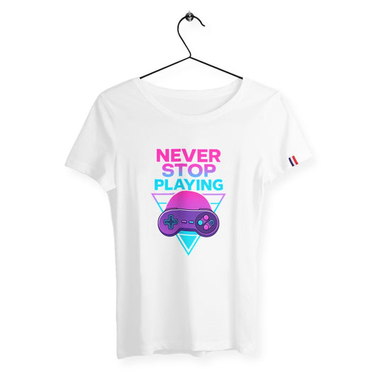 T-shirt blanc premium pour femme avec le message "NEVER STOP PLAYING". Design fun en rose fluo et bleu cyan, accompagné d’une manette rétro violette sur fond néon style années 80. Parfait pour les gameuses stylées !
