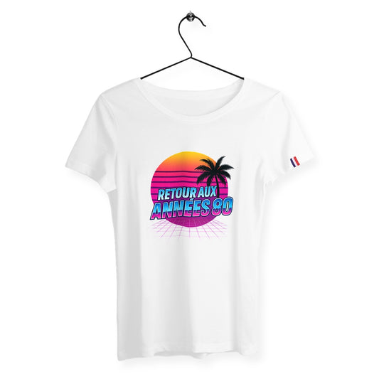 T-shirt femme blanc suspendu sur cintre avec design rétro “Retour aux Années 80” style synthwave, soleil couchant et palmier. Coton bio, fabriqué en France, coupe féminine.