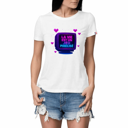 Femme portant un t-shirt blanc avec un visuel rétro pixel art et l’inscription « LA VIE EST UN JEU PIXELISÉ » sur un écran cathodique entouré de cœurs roses.